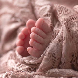 Close-up of a newborn baby's tiny feet, wrapped in a light pink knitted blanket. Taken by Sacramento maternity and newborn photographer Kristina Martin