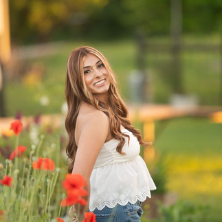 Senior portrait session at a flower farm in Sheridan, California with seasonal flowers, a greenhouse, arches, and warm sunset light.