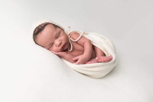 A gallery of newborn session images featuring a swaddled baby in simple, cozy setups. The photos capture a variety of angles, showing the baby peacefully resting in natural, comfortable poses. Some images are taken on a soft white backdrop, while others include a blue background or warm, textured blankets taken by Sacramento Maternity and Newborn photographer Kristina Martin Photography.