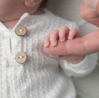 Close-up of a newborn baby's tiny hand being held gently by her dads hand. Taken by Sacramento maternity and newborn photographer Kristina Martin