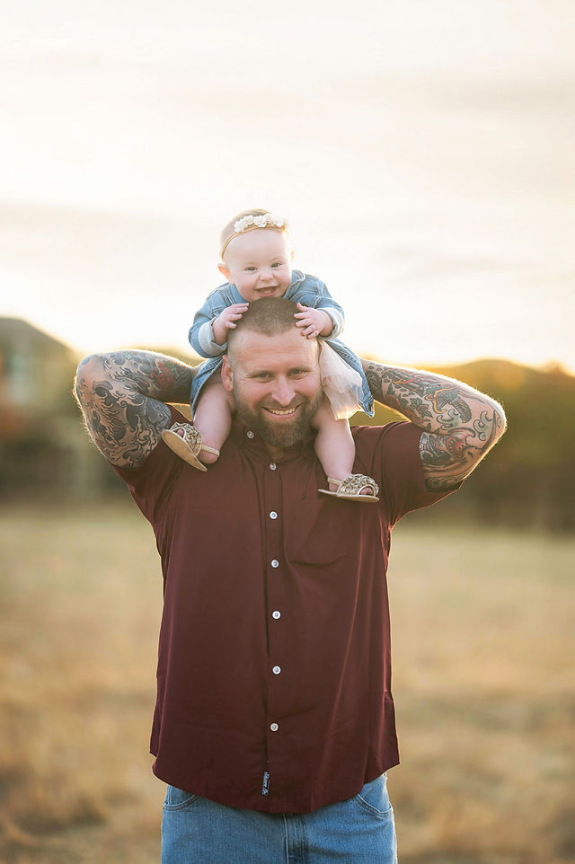 Sacramento family photographer captures a family of three in a local park at sunset with golden dry grass and warm natural tones.