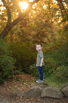 Family of four posing together during a fall family photography session surrounded by golden trees at the Iris Farm in Loomis, California.