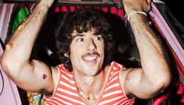 Australia Eurovision 2025 artist Go-Jo wears a striped singlet as he holds an ice cream truck as part of his Milkshake Man video.