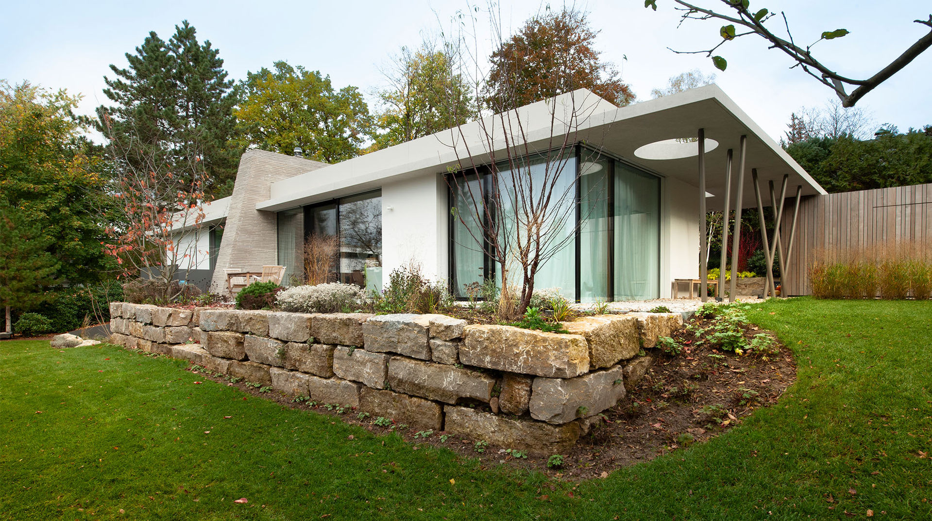 GRIMM ARCHITEKTEN BDA | rahmenlose Fenster, Josko, Eingang, schräge Stützen, auskragendes Vordach, Sichtbeton, Ganzglasecke, Öffnungen in Decke, verklinkerter Kamin, Trockenmauer