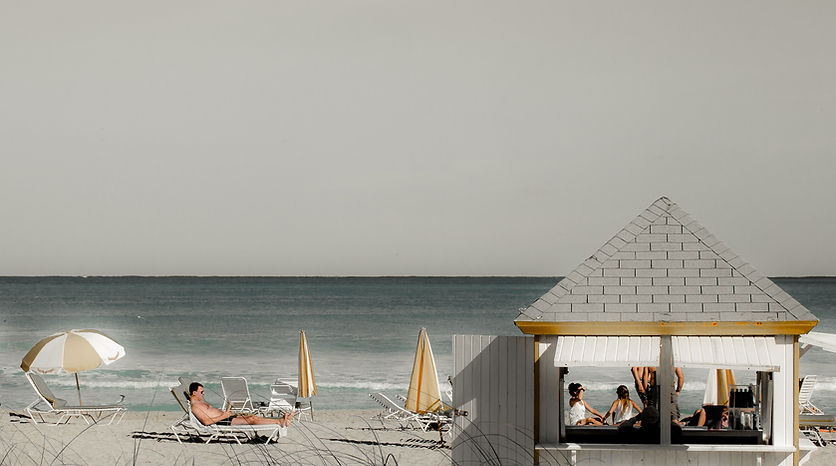 A man reading a book at the beach with his family around