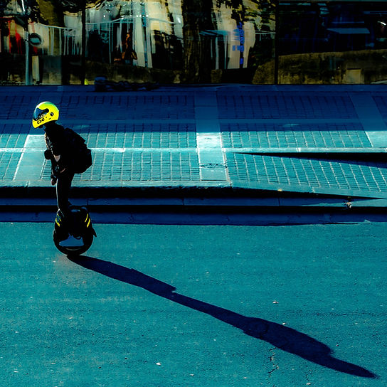 a man on an electric wheel with a yellow helmet in a street