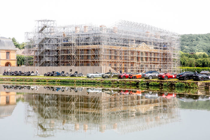 Works at the castle of Dampierre, France, with luxury cars parked