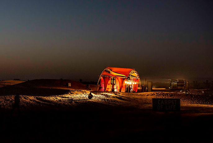 A vendor of carpet in the night, waiting for customers in the desert