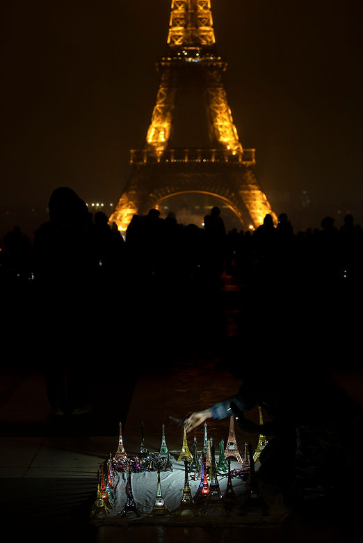 the hand of an eiffel tower vendor with little towers and the eiffel tower in the background