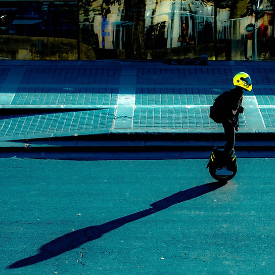a man on an electric wheel with a yellow helmet in a street
