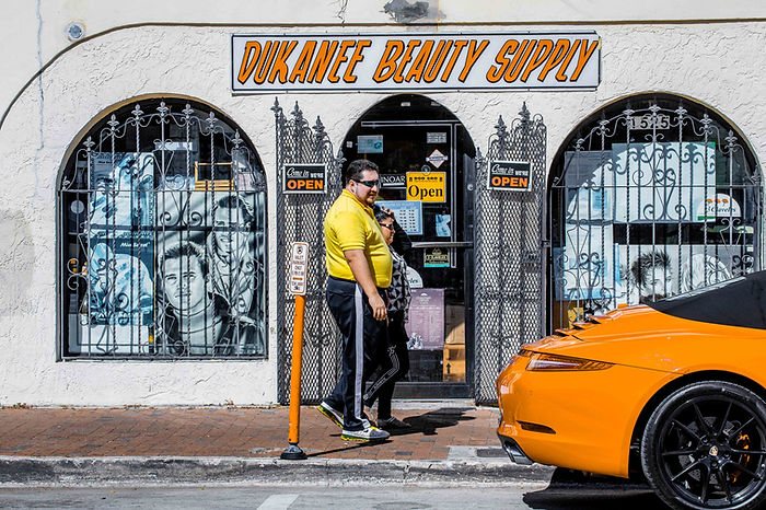 A man looking at a supercar in front of a beauty shop