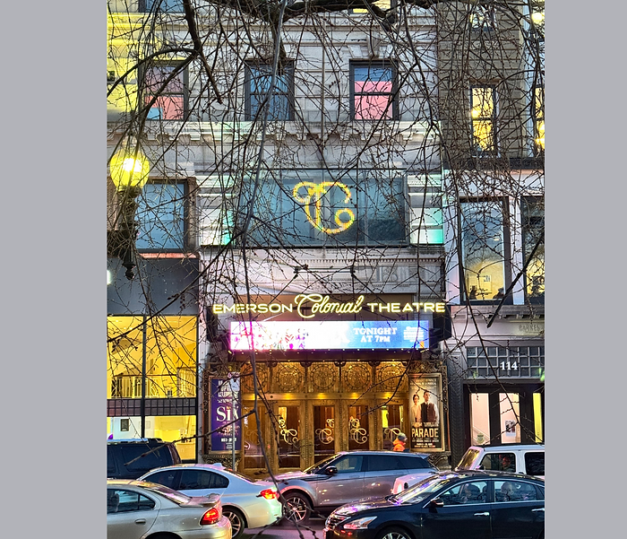 The Colonial Theatre during the day with traffic in front of the theatre. 