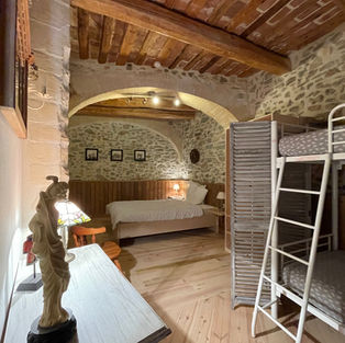 Bedroom with stone walls, wooden floors a queen and a bunk bed