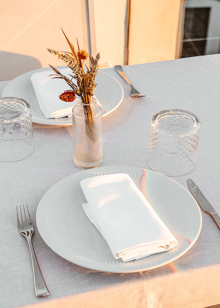Mesa elegante puesta para dos, con flores secas bajo luz cálida.