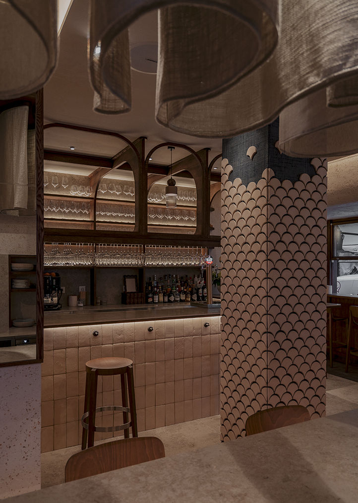 Barra de bar moderna con mostrador de azulejos y columna decorativa.