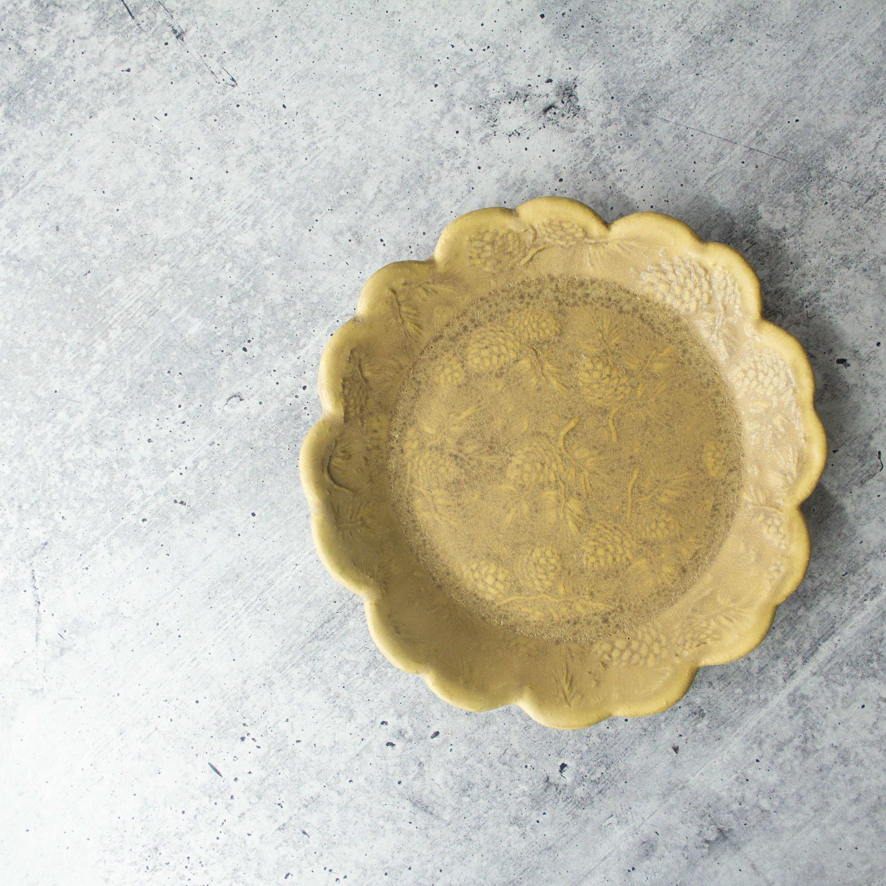 handmade ceramic sandwich plate with scalloped edge and pine cone texture, glazed finish