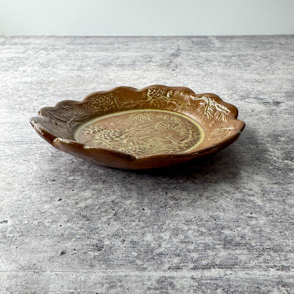 handmade ceramic tapas dish with scalloped edge and detailed pine cone texture, rustic glaze finish.