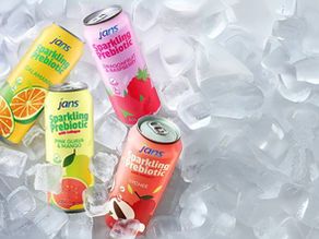 Four sleek cans of Jans Sparkling Prebiotic drinks including Calamansi, Dragonfruit & Raspberry, Pink Guava & Mango, and Lychee flavors chilling beautifully on a bed of fresh ice cubes.