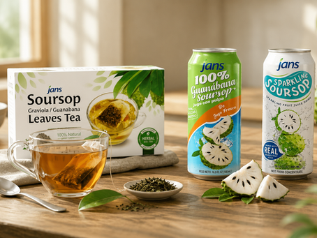 A retail product display featuring a box of Jans Soursop Leaves Tea next to a glass teacup, a green can of Jans 100% Guanabana Soursop Juice, and a sleek can of Jans Sparkling Soursop on a sunlit wooden table.