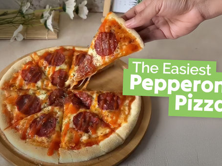 Homemade pepperoni pizza with a slice being pulled away to show the gooey cheese and zesty chili sauce.