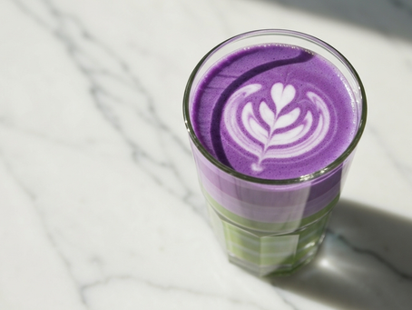 A beautiful layered ube and matcha latte with delicate latte art on top, showing a vibrant and creamy beverage.