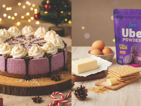 A creamy purple ube cheesecake topped with whipped cream, chocolate sauce, and toasted coconut, next to a bag of Ube Powder.