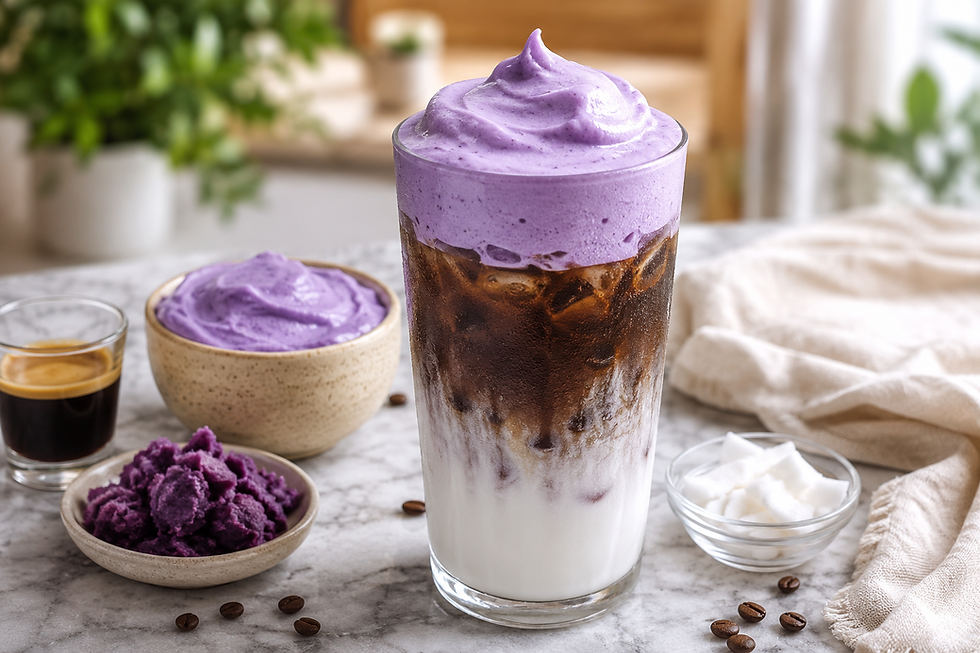 A glass of iced coffee topped with a thick, beautifully dolloped swirl of purple ube coconut cream cold foam, surrounded by an espresso shot, a bowl of ube halaya, and coconut chunks.