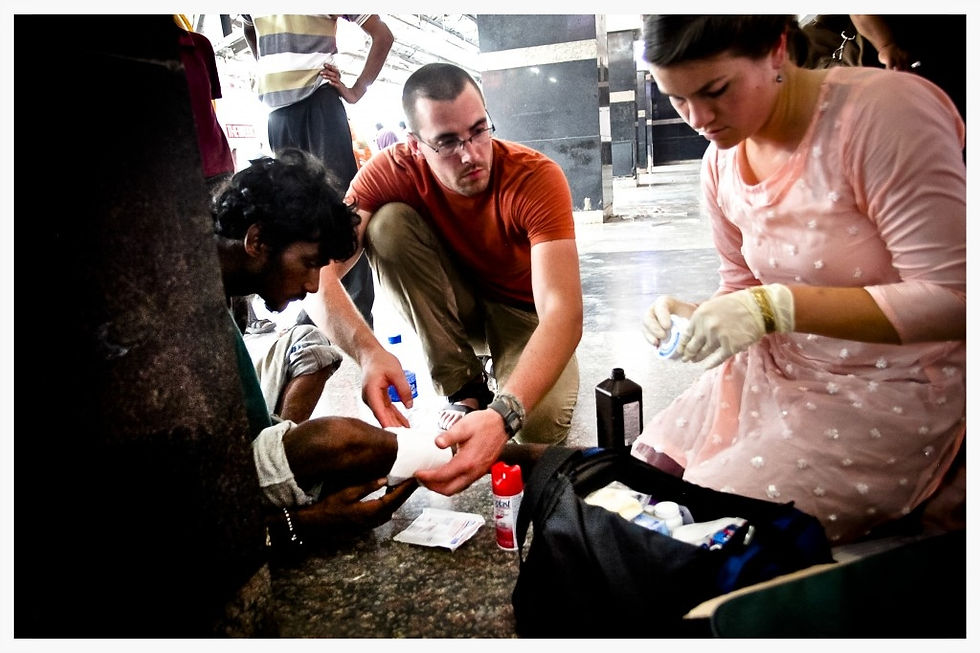 Grant Dailey assists Rebekah Davis in mending a wound on an injured elderly man in India. Basic wound care is life-saving in third world environments without proper sanitation, access to water and basic medical supplies. 