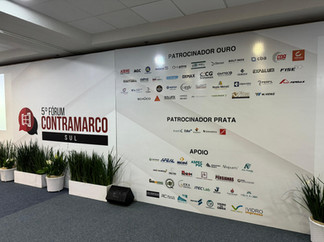 Auditório de palestra com telões do evento, cadeiras e sacolas