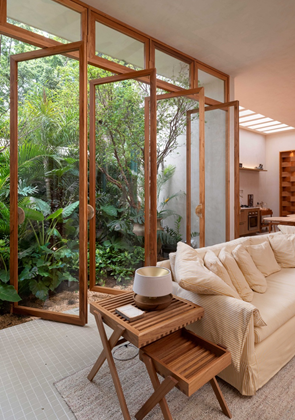 Sala de estar com sofá cor nude e porta de vidro com perfil de madeira