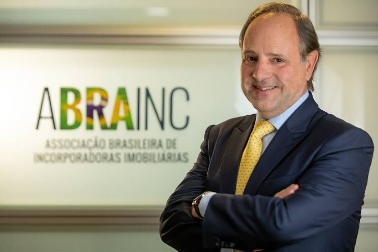 Presidente da Abrainc em frente ao logo da associação