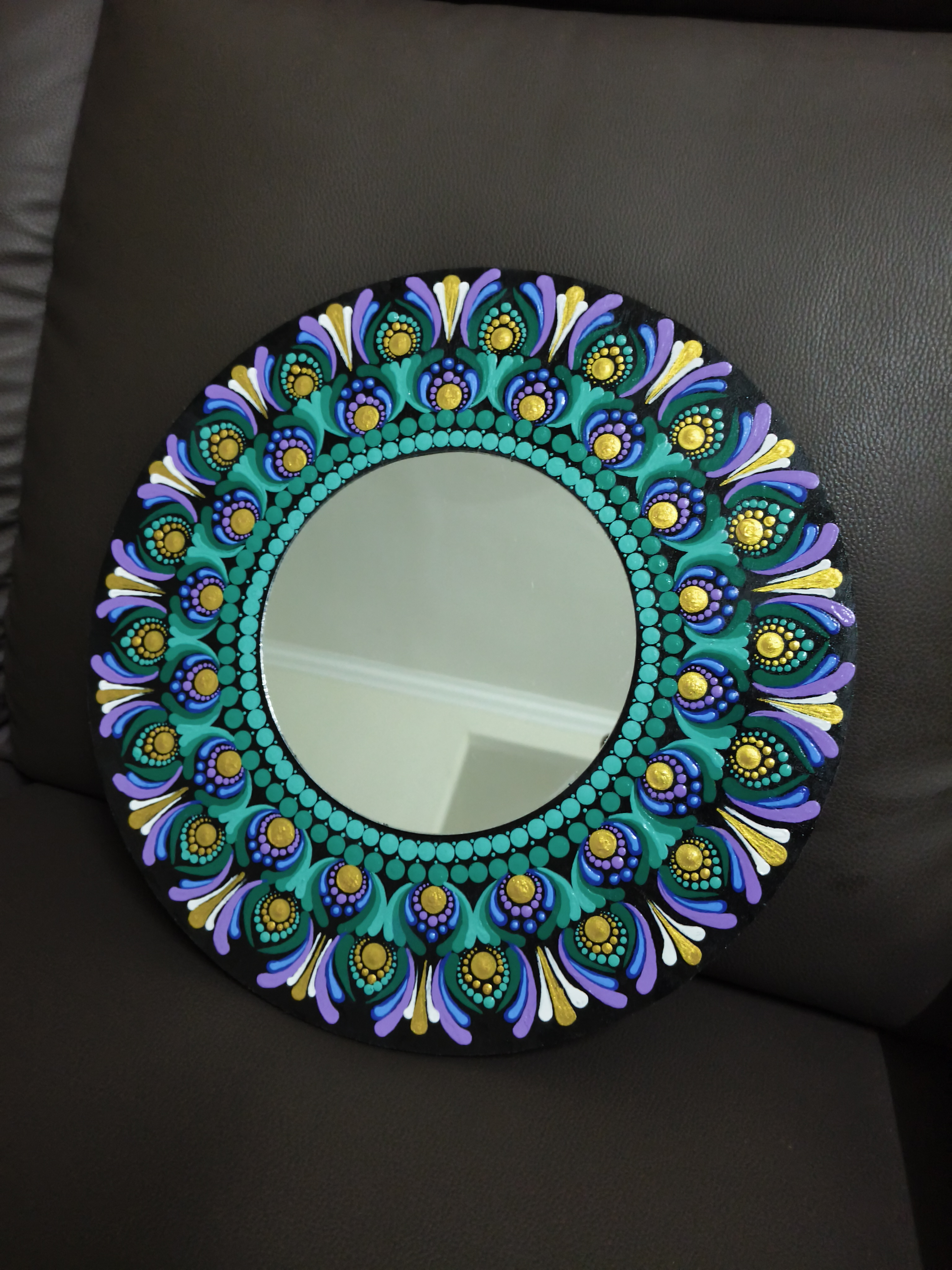 The Peacock mirror by Deishiga Devendran, circular mirror with ornate, peacock-color frame