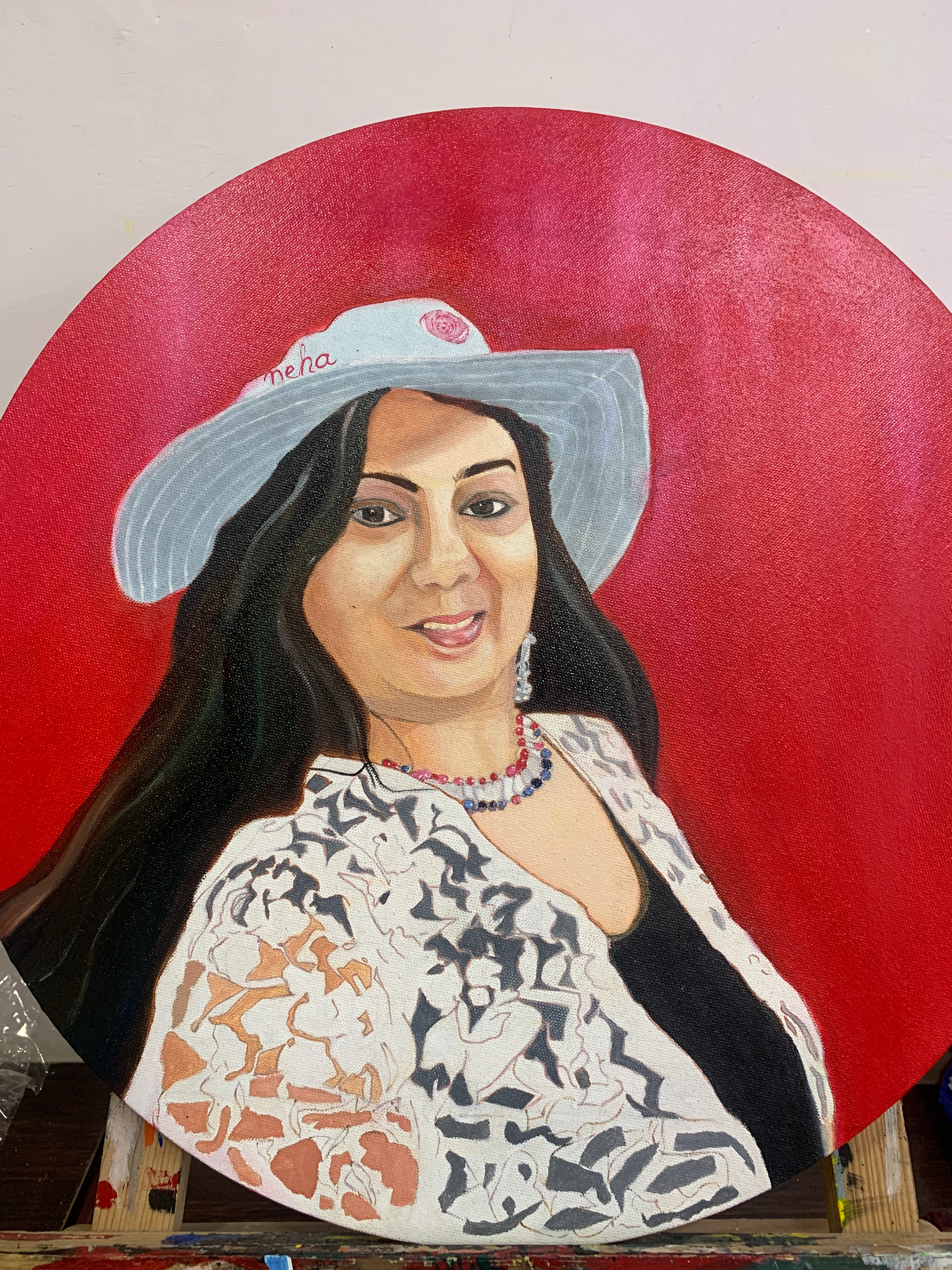Self portrait in acrylic by Neha Saini, woman with long dark hair, light blue hat, beaded necklace, on vibrant red background