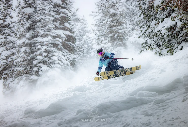 Erin Skiing down a mountain in the snow with trees behind her