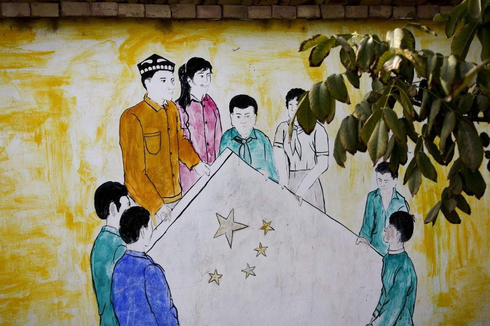 A mural depicting Uighur and Han Chinese men and women carrying the national flag of China in Hotan.