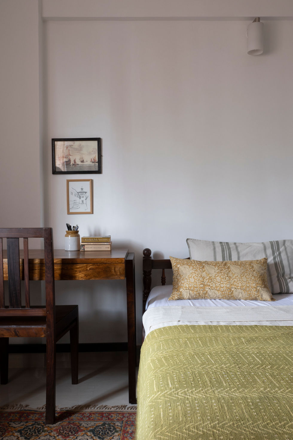 a stack of books on a desk next to a bed