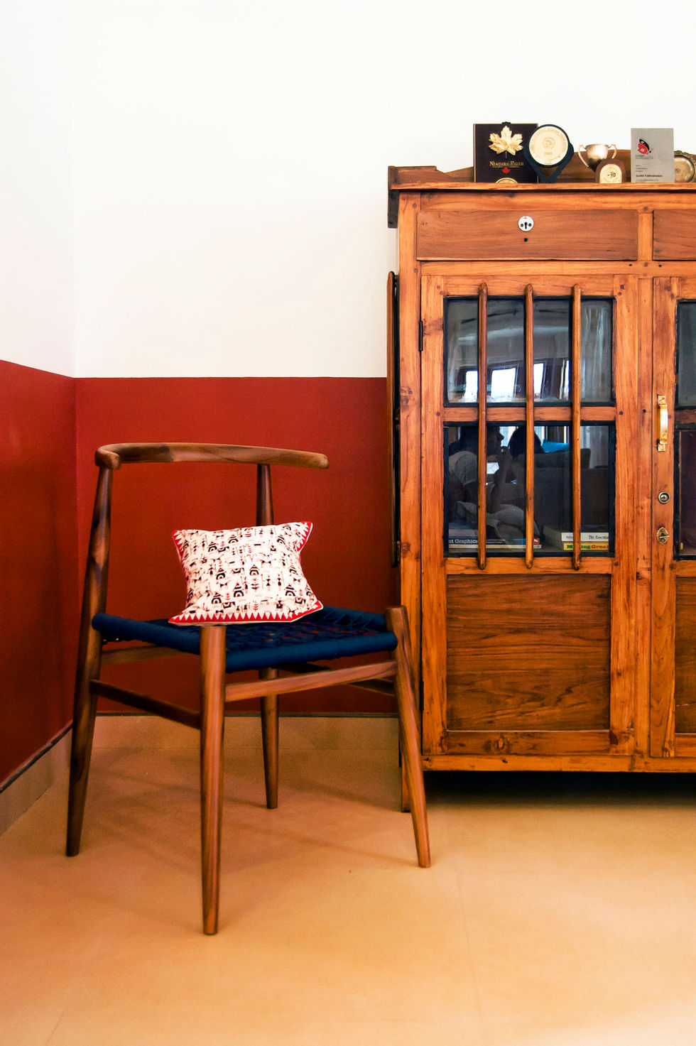 a chair with a pillow on it sits next to a wooden cabinet