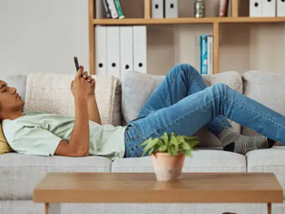Gen Z young person using a smartphone while relaxing at home