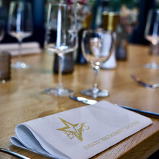 Gefaltete Serviette mit Stern-Logo und 'Enjoy your meal' auf gedecktem Holztisch.