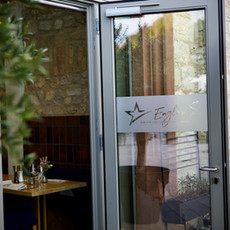 Glastür mit Eagle's Nest Logo, Eingang zu Restaurant mit Steinfassade.