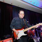 Grupo KaChe guitarist performing live during an event at a Houston venue as part of the band's Latin and variety music performance.