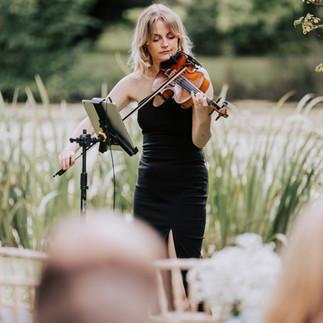 a woman playing violin in a garden