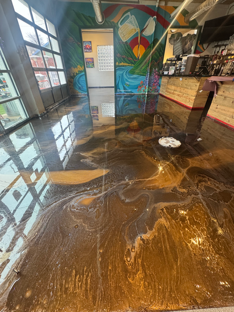 Silver metallic epoxy floor in a restaurant with a bar and exposed wood ceiling