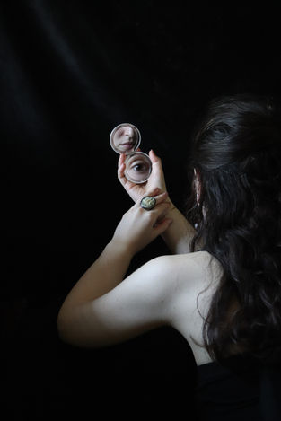 a drametic portrait of a woman from the back with a hand mirror