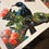 Thumbnail: Tūī in Pōhutukawa NZ Bird Paint by Number Kit Canvas part painted on a table.