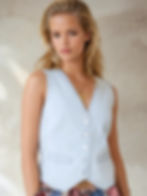 Young woman in a denim vest, posing for a portrait, looking confident.