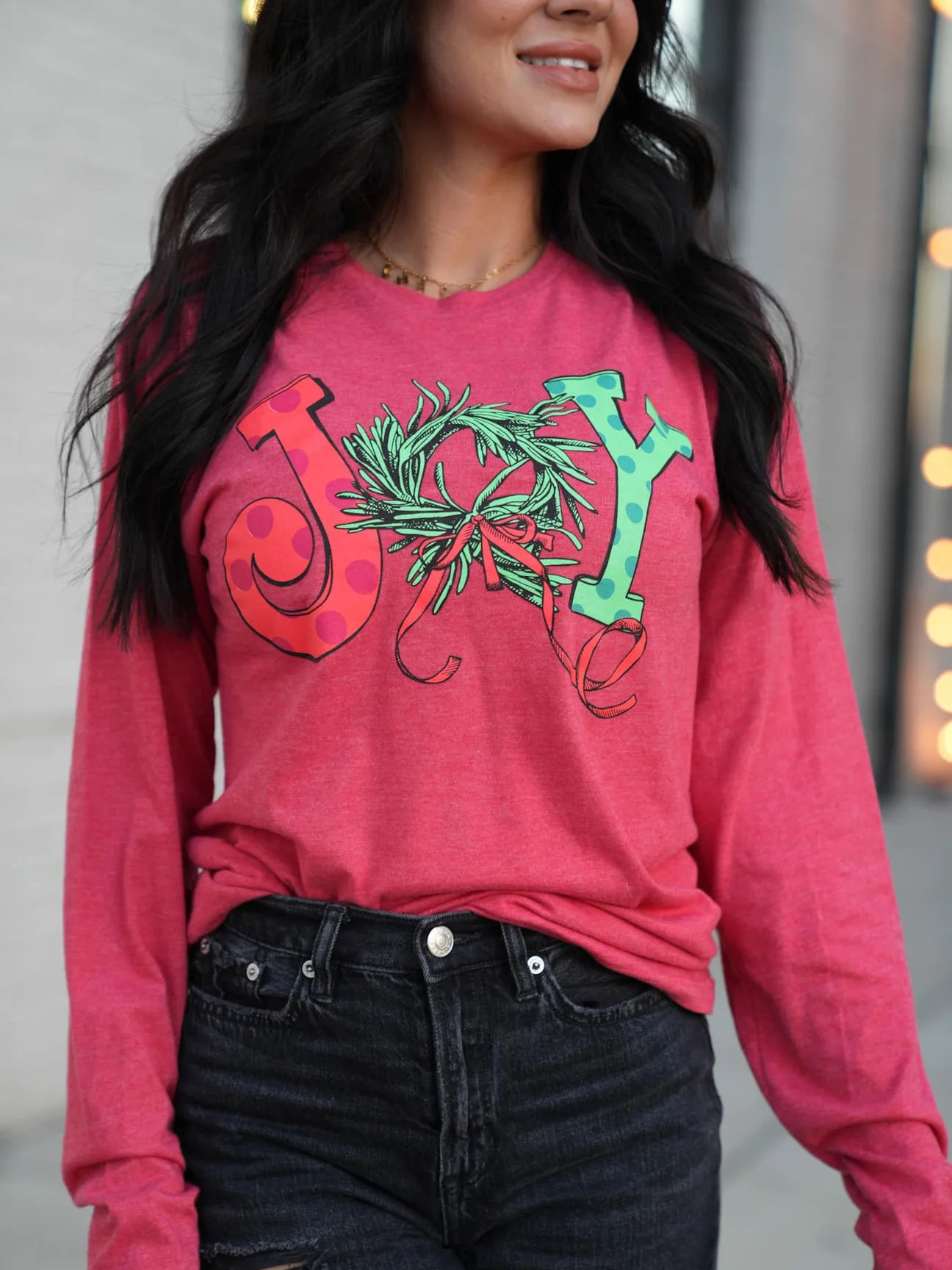 Woman wearing pink long sleeve JOY shirt with wreath Holiday Joy Tee.
