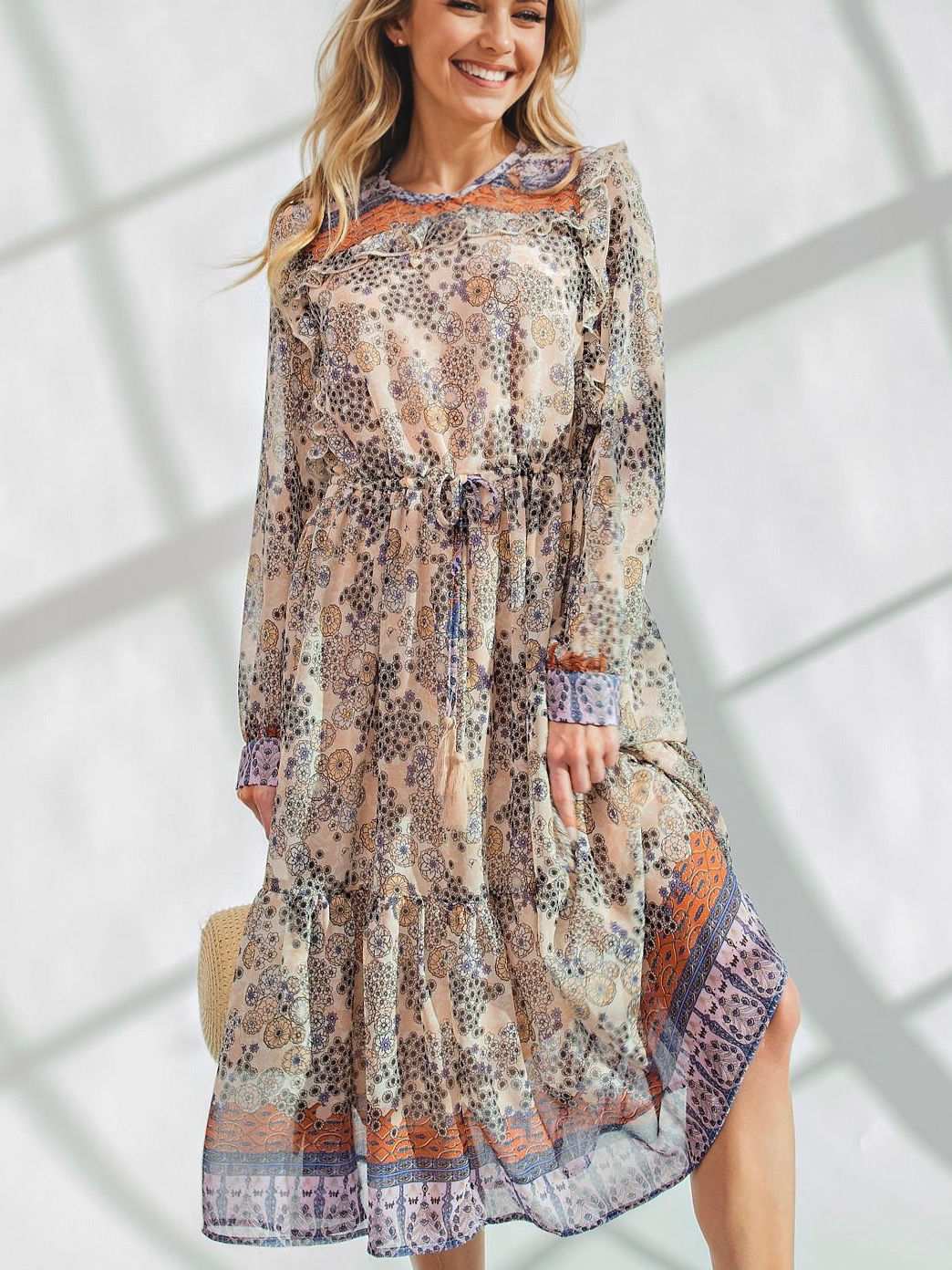 Woman wearing floral print dress stands; light and shadows across her body.