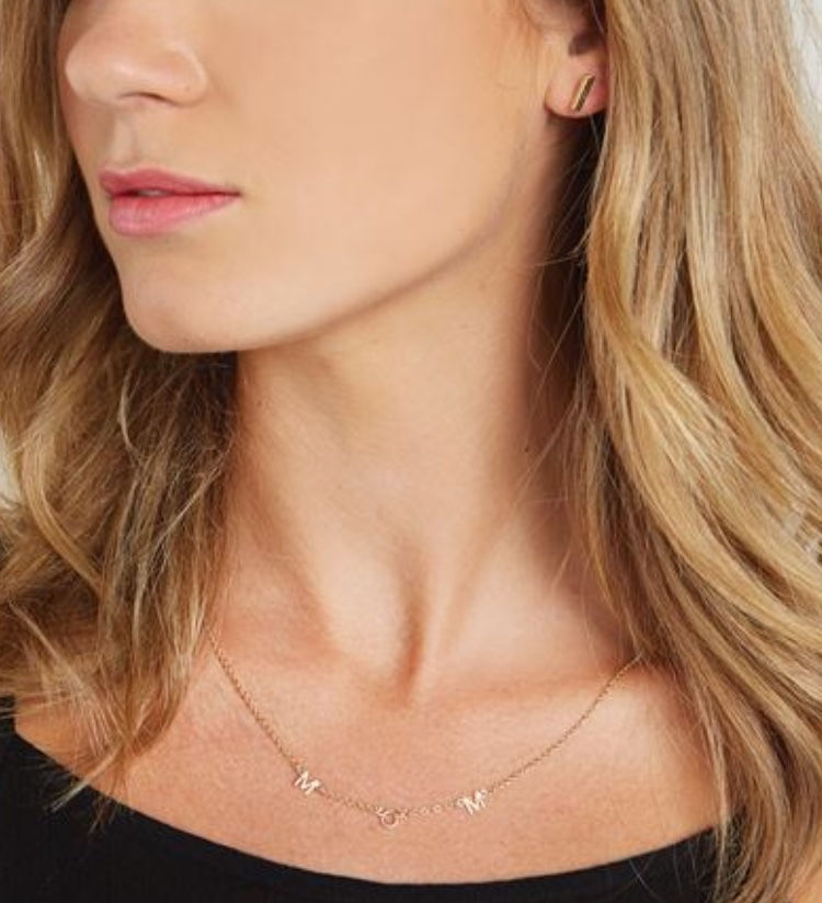 Elegant woman wearing gold necklace and earrings looking to the side.