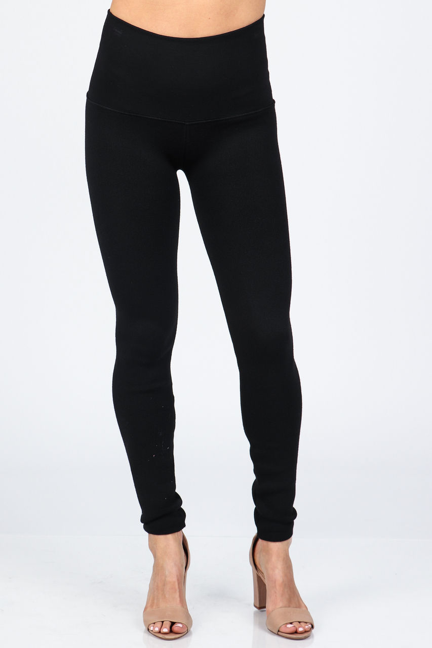 Woman wearing black leggings posing for a fashion image with perfect form.